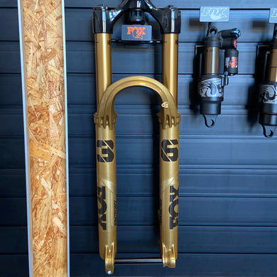 FOX 36 Float Factory GRIP X suspension fork in limited edition Podium Gold, featuring 29-inch wheel compatibility, 160 mm travel, Kashima-coated stanchions, and robust magnesium lowers. The fork displays distinctive gold finish, black decals, and precision adjustment dials on the crown, designed for aggressive all-mountain and enduro riding