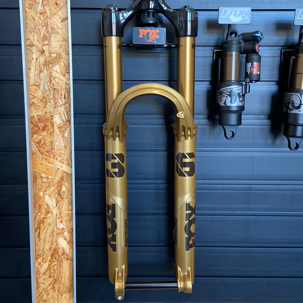 FOX 36 Float Factory GRIP X suspension fork in limited edition Podium Gold, featuring 29-inch wheel compatibility, 160 mm travel, Kashima-coated stanchions, and robust magnesium lowers. The fork displays distinctive gold finish, black decals, and precision adjustment dials on the crown, designed for aggressive all-mountain and enduro riding